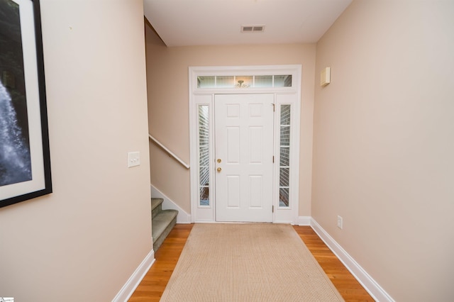 entryway with light wood-style floors, stairway, and baseboards
