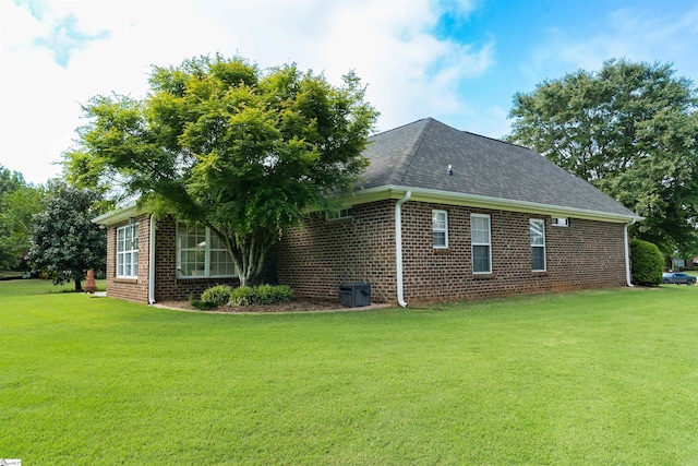 view of home's exterior featuring brick siding, a lawn, and roof with shingles