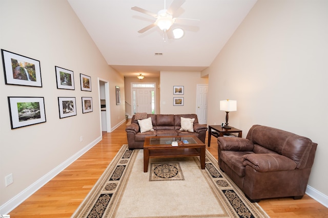 living room with light wood-type flooring, lofted ceiling, a ceiling fan, and baseboards