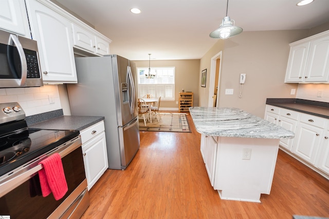 kitchen featuring stainless steel appliances, light wood-style flooring, a chandelier, a center island, and white cabinetry