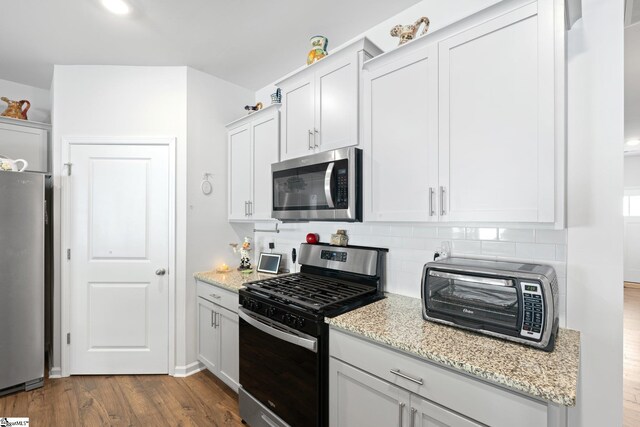 51 Oak Edge Ln, Greer, SC 29651 - kitchen with stainless steel appliances, decorative backsplash, dark wood-style floors, light stone countertops, and white cabinetry