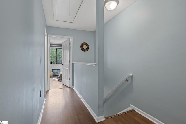 hall with attic access, an upstairs landing, wood finished floors, and baseboards