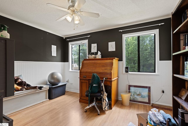 home office featuring wainscoting, a textured ceiling, wood finished floors, plenty of natural light, and ceiling fan