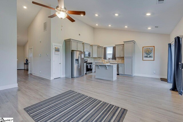 kitchen with stainless steel appliances, gray cabinets, open floor plan, high vaulted ceiling, and recessed lighting