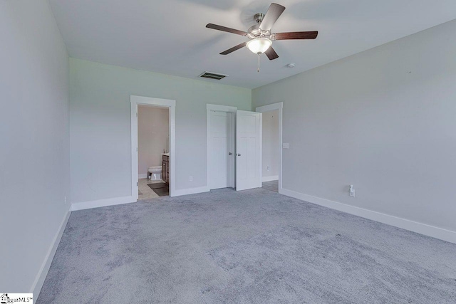 unfurnished bedroom with baseboards, carpet flooring, connected bathroom, and a ceiling fan