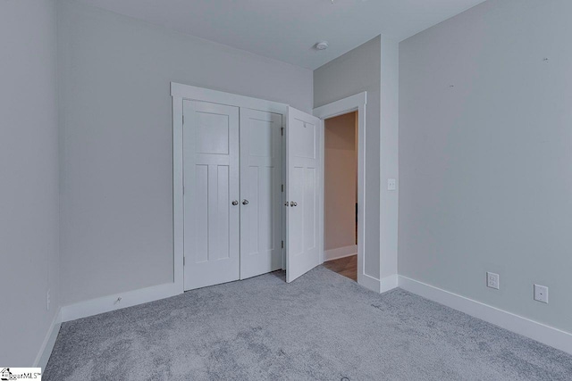 unfurnished bedroom featuring carpet flooring, baseboards, and a closet