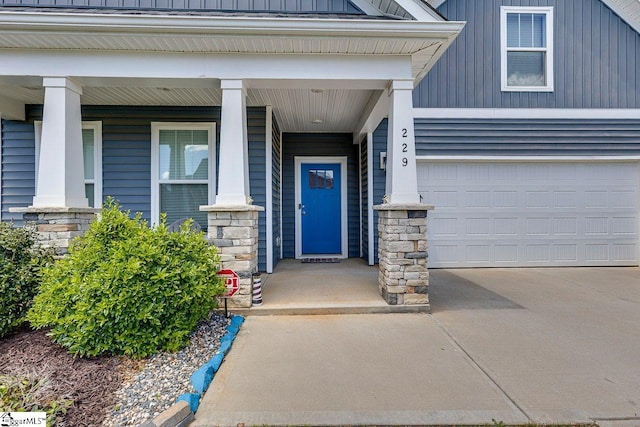 property entrance with stone siding, driveway, a porch, board and batten siding, and a garage