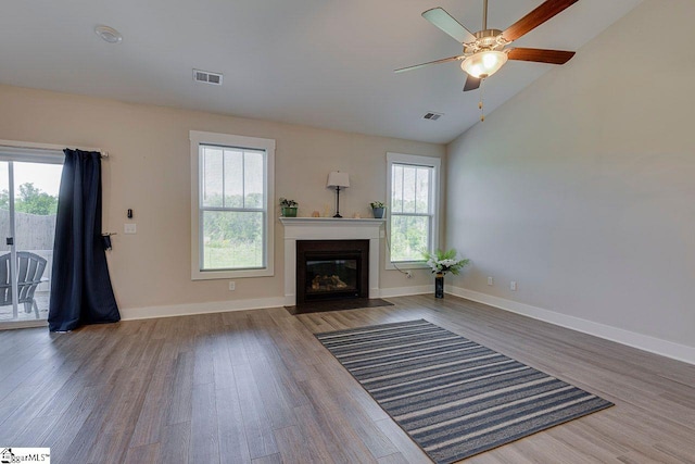 unfurnished living room with wood finished floors, a fireplace with flush hearth, lofted ceiling, ceiling fan, and baseboards