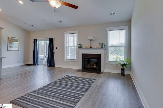 unfurnished living room featuring wood finished floors, a fireplace with flush hearth, a ceiling fan, lofted ceiling, and baseboards