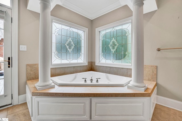 bathroom featuring decorative columns, crown molding, a bath, and baseboards
