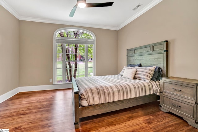 bedroom featuring crown molding, dark wood-style flooring, baseboards, and a ceiling fan