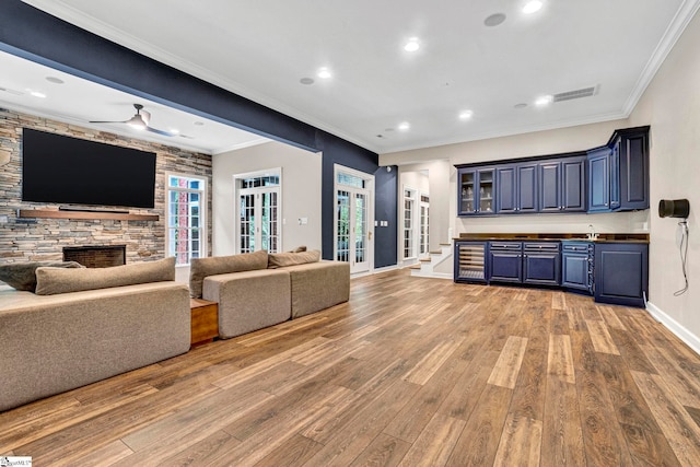 living room with light wood-type flooring, baseboards, ceiling fan, french doors, and a stone fireplace