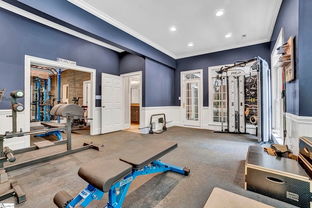 workout room featuring crown molding, a decorative wall, recessed lighting, wainscoting, and carpet