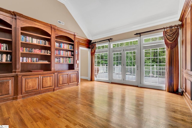 empty room featuring vaulted ceiling, crown molding, plenty of natural light, and light wood-type flooring