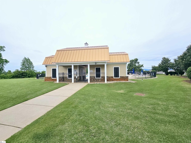 view of front of house with a standing seam roof, covered porch, a front lawn, and a chimney