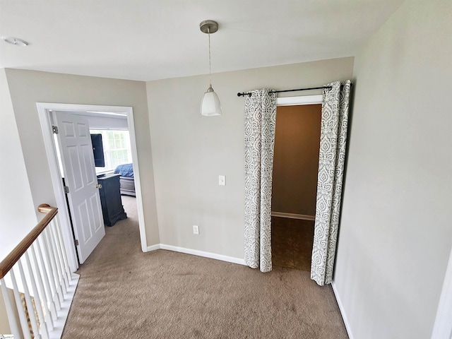 unfurnished dining area featuring carpet flooring and baseboards