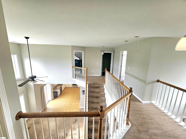 corridor with an upstairs landing, baseboards, and carpet flooring