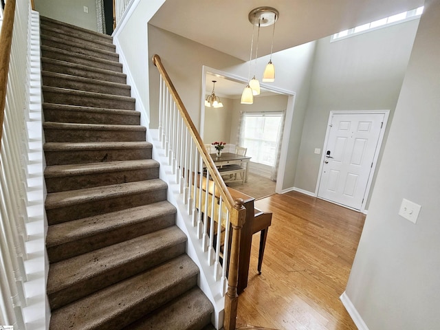 entryway featuring stairs, light wood-style floors, a chandelier, and baseboards