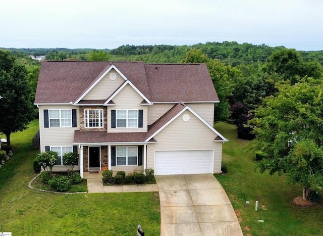 traditional-style home featuring driveway, a front yard, roof with shingles, and a wooded view