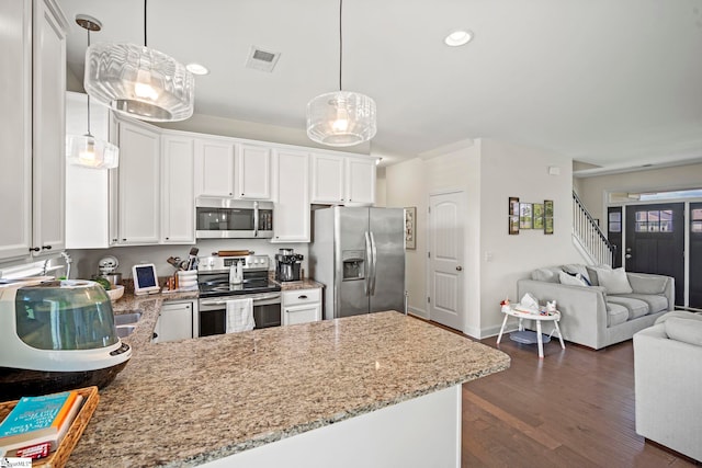 kitchen featuring stainless steel appliances, open floor plan, a peninsula, dark wood-style floors, and light stone countertops