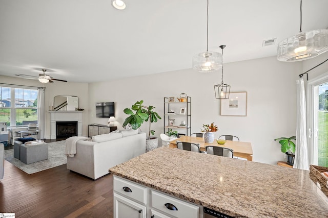 kitchen with healthy amount of natural light, white cabinets, dark wood-style floors, and hanging light fixtures