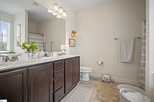 full bath with double vanity, baseboards, and toilet