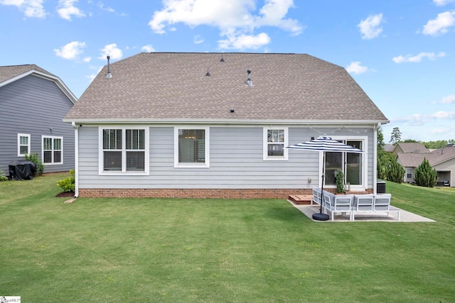 rear view of property featuring a yard, roof with shingles, and a patio area