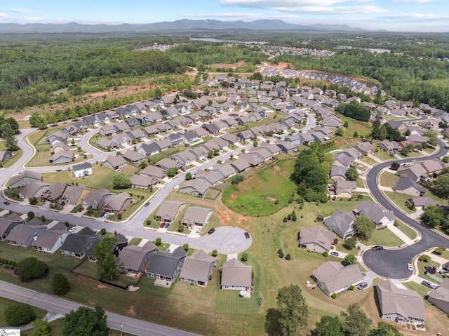 aerial overview of property's location with mountains, nearby suburban area, and a forest