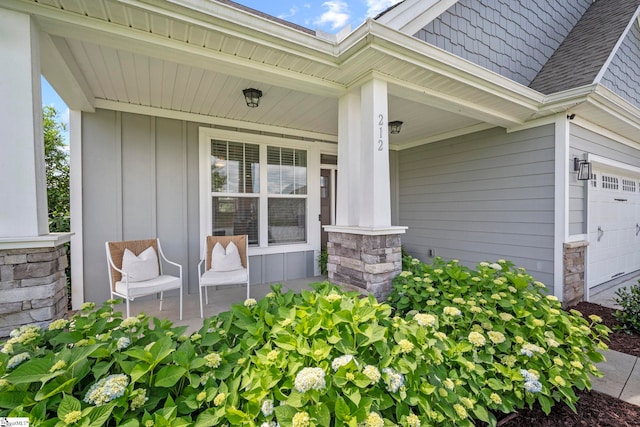 entrance to property featuring covered porch, a garage, board and batten siding, and roof with shingles