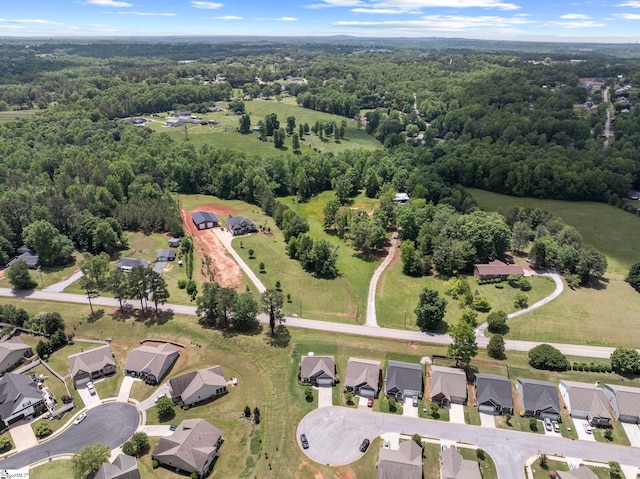 aerial view of property's location featuring a forest and nearby suburban area