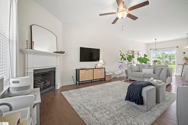 living room featuring a ceiling fan, a fireplace, and dark wood-style flooring