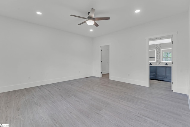 unfurnished bedroom with light wood finished floors, baseboards, ensuite bath, recessed lighting, and a spacious closet