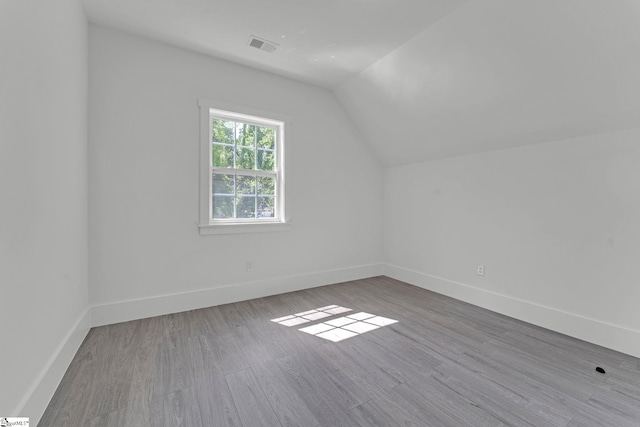 additional living space featuring vaulted ceiling, wood finished floors, and baseboards