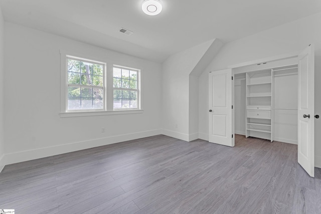 unfurnished bedroom featuring wood finished floors, baseboards, and a closet