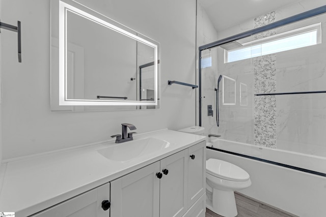 full bath with toilet, vanity, and combined bath / shower with glass door