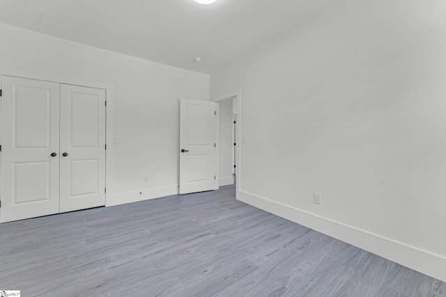 unfurnished bedroom with light wood-style floors, baseboards, and a closet