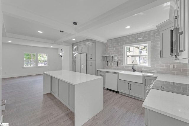 kitchen with a sink, white appliances, tasteful backsplash, light wood-style flooring, and beam ceiling
