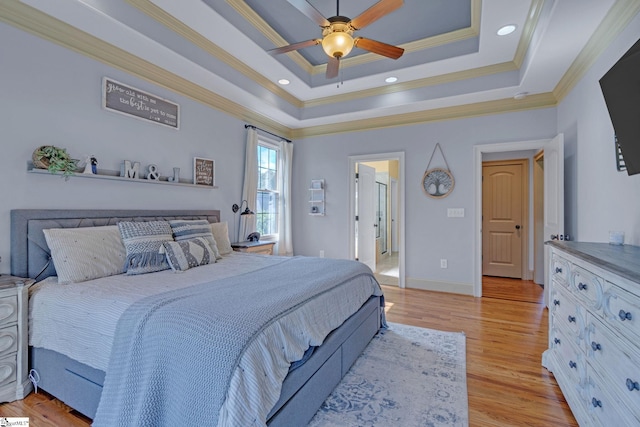 bedroom featuring ornamental molding, light wood-style flooring, a tray ceiling, baseboards, and a ceiling fan