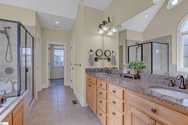 full bathroom with a shower stall, double vanity, tile patterned flooring, and baseboards