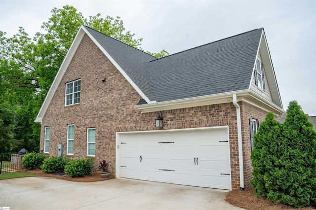 view of property exterior featuring driveway, brick siding, roof with shingles, and fence