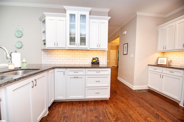 kitchen featuring a sink, white cabinets, dark stone countertops, dark wood-style floors, and decorative backsplash