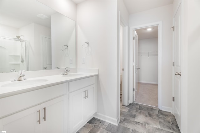 737 Rockhurst Way, Woodruff, SC 29388 - bathroom with baseboards, double vanity, stone finish floors, and a walk in closet