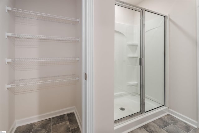 737 Rockhurst Way, Woodruff, SC 29388 - bathroom with stone tile floors, a shower stall, baseboards, and a walk in closet