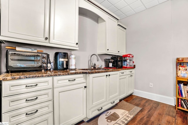 5 Laurelcrest Ln, Travelers Rest, SC 29690 - kitchen with a sink, dark wood-style flooring, baseboards, dark stone countertops, and white cabinets