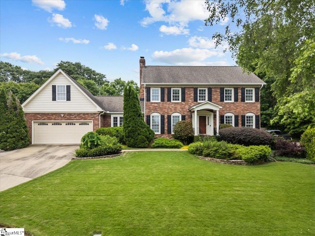 view of front of property featuring brick siding, driveway, a chimney, and a front lawn