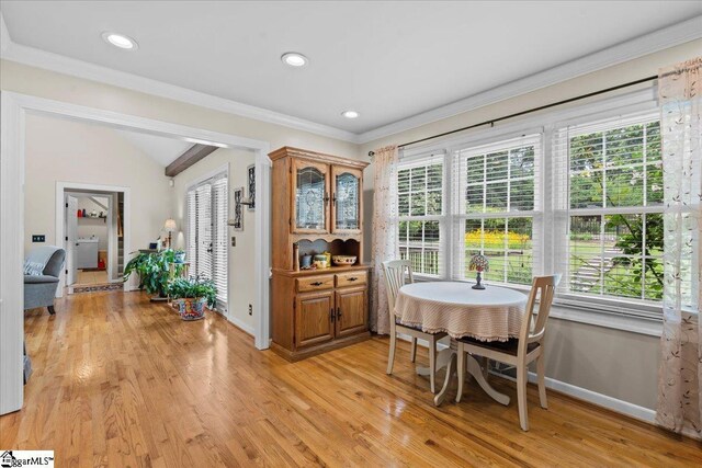 dining room featuring baseboards, healthy amount of natural light, light wood-style flooring, crown molding, and lofted ceiling