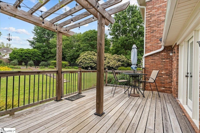 wooden terrace with a pergola, outdoor dining space, and view of scattered trees