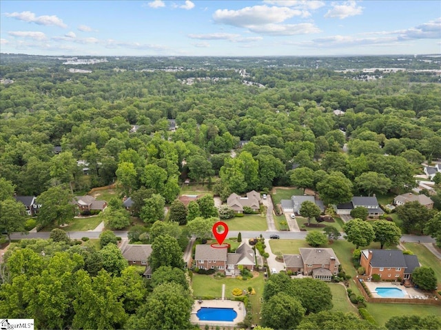 aerial perspective of suburban area with a pool and a heavily wooded area