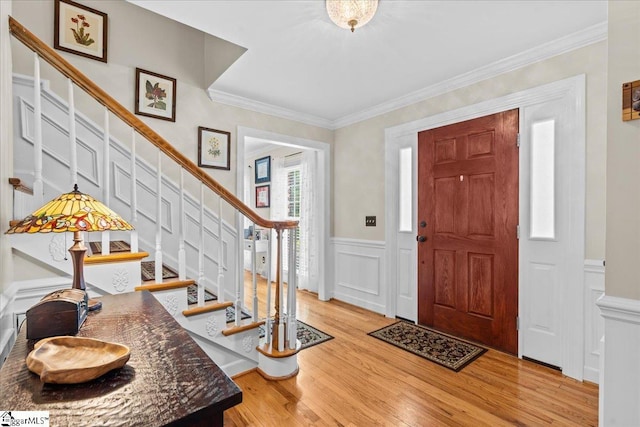 entrance foyer featuring a decorative wall, stairs, light wood-type flooring, wainscoting, and crown molding