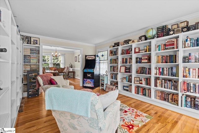 sitting room with ornamental molding, a chandelier, and wood finished floors